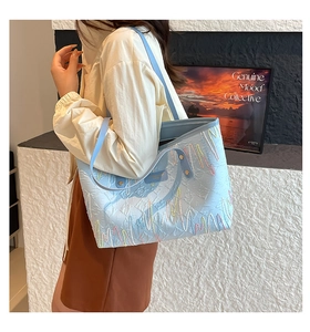 Detail of light blue tote bag with colorful wavy embroidery and embossed texture