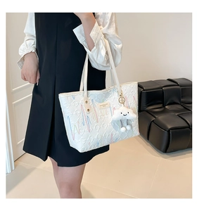 Detailed view of white quilted tote bag with rainbow embroidery and cloud charm