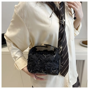Detailed close-up of a black shell bag with 3D rosettes and gold metal clasp closure