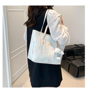 Close-up of white tote bag with colorful wave embroidery and plush cloud charm detail