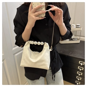 Detail of white vintage shoulder bag featuring large pearl handles and gold chain strap