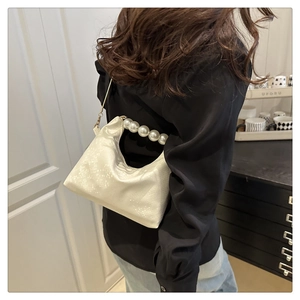 Detail shot of the white snake texture leather bag with elegant pearl chain handle strap