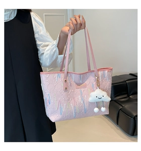 Detail of pink embroidered tote bag featuring wave patterns and a cloud plush charm