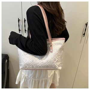 Detail of pink and white jacquard tote bag with geometric patterns and metal rivets