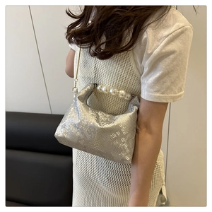 Detailed view of silver faux snake leather bag featuring pearl handle and gold chain strap