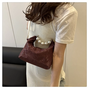 Close-up of wine red snakeskin texture bag with pearl handle and gold chain strap