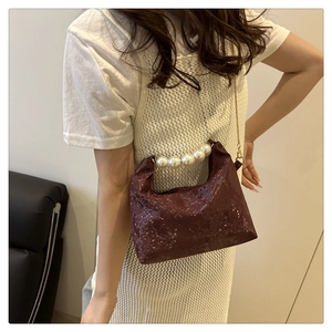 Detail of dark burgundy snakeskin texture bag with large pearl handle and gold chain strap