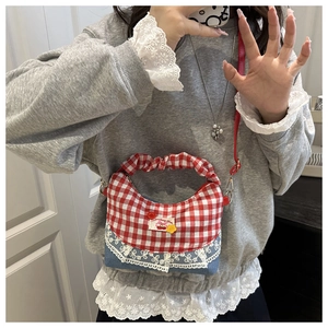 Detail of red gingham and blue denim crossbody bag with delicate lace and cherry patch