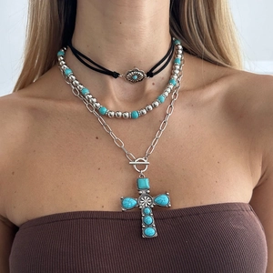 Close-up of bohemian layered necklace with turquoise cross pendant on model