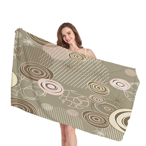 Olive green beach towel with geometric abstract patterns shown by a female model