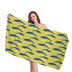 Bright yellow microfiber beach towel with seamless dolphin pattern held by a model