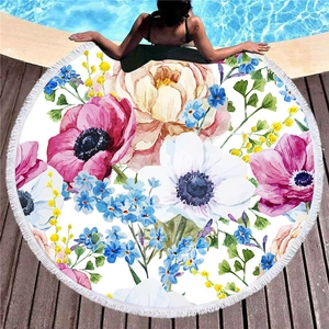 Round thick beach towel with tropical floral patterns and white tassels by the pool