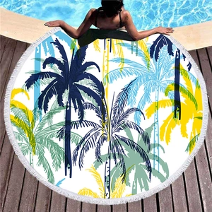 Round beach towel with tropical palm leaves, white tassels, and poolside vacation design