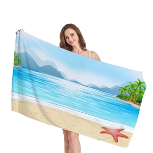 Telo da mare spesso con motivo di palme e paesaggio marino tenuto da una modella