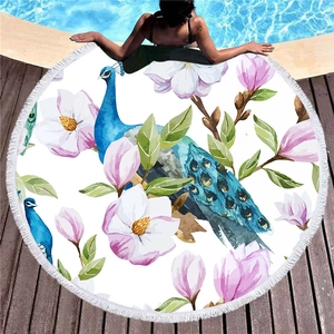 Rundes Strandtuch mit blauem Pfau, pinken Magnolienblüten und weißen Fransen am Rand