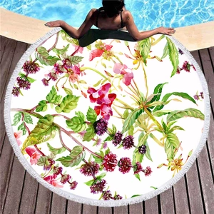 Rundes Strandtuch mit Aquarellblumen und weißen Fransen auf einem Holzdeck am Pool