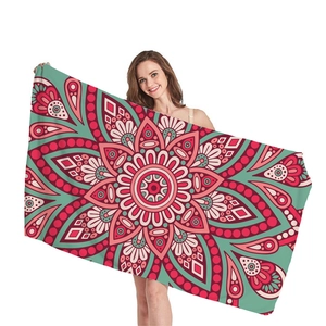 Ethnic mandala beach towel with red and turquoise geometric floral pattern held by model