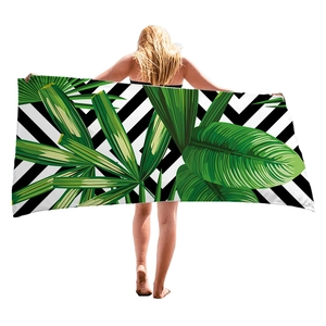 Dickes Strandtuch mit tropischen Palmenblättern und Zickzackmuster gehalten von einem Model