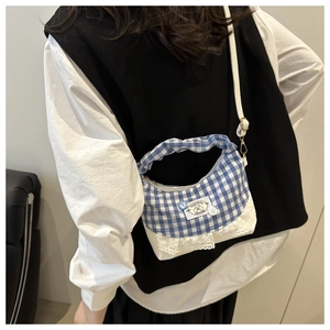 Detail of blue plaid pleated handbag featuring delicate lace trim and sweet baby patch