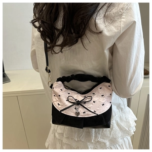 Detail of pink bow handbag with heart charm and black ribbon accent in lifestyle setting
