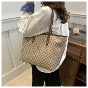 Close-up of vintage monogram tote bag with brown leather handles and classic pattern