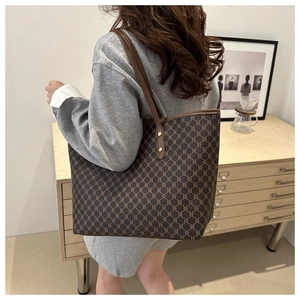 Woman carrying large vintage brown monogram tote bag over shoulder in modern home setting