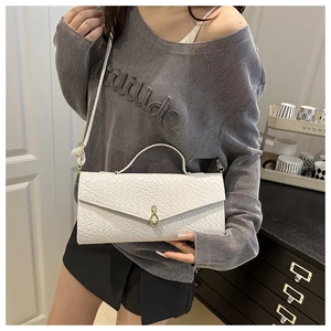 Détail du sac blanc à motif crocodile avec fermoir doré et poignée supérieure chic