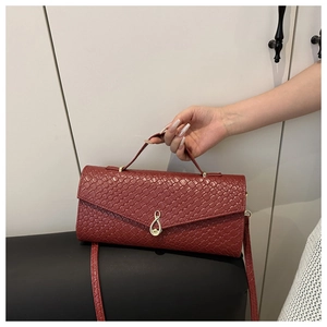 Détails de la texture tissée rouge vin et du fermoir doré de ce sac à main pour femme