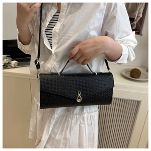 Detail of black faux leather textured handbag featuring a gold infinity twist lock