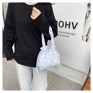 Close-up of blue floral and plaid drawstring handbag with elegant lace trim details