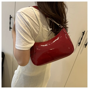Détail du sac hobo en cuir verni rouge avec chaîne dorée et finition brillante