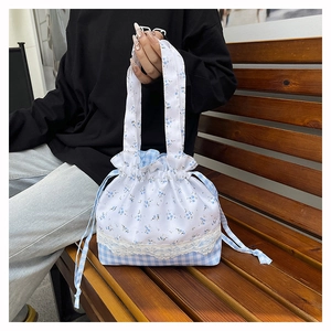 Detail view of floral drawstring handbag with blue lattice patchwork and lace trim