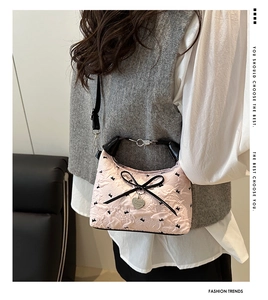 Sac bandoulière matelassé rose avec nœud noir et pendentif cœur porté par le mannequin