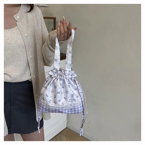 Close-up of drawstring bag showing purple floral and plaid patchwork with lace detail