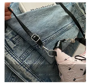 Close-up of adjustable glossy black shoulder strap with silver metal buckle on a floral bag