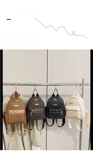 Détail de mini sacs à dos en quatre couleurs avec imprimé et clous dorés