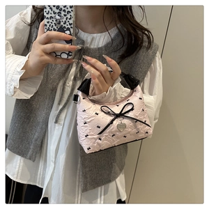 Detail view of pink ruffled bucket bag with black bows and heart pendant