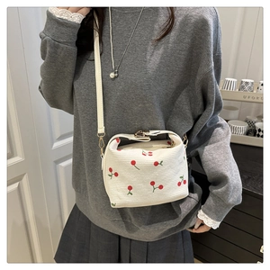 Detail view of canvas shoulder bag with red cherry embroidery and adjustable strap