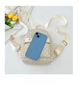 Vue détaillée du mini sac à dos crème avec comparaison de taille avec un smartphone bleu