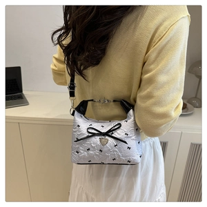 Detail view of the black and white mini bucket bag with ribbon bow and heart pendant
