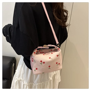 Detail of pink woven cherry handbag showing texture and pink leather straps on model