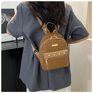 Détail d'un mini sac à dos marron à motifs avec clous dorés et larges bretelles