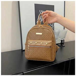 Détail d'un mini sac à dos marron avec logo imprimé et rivets métalliques dorés