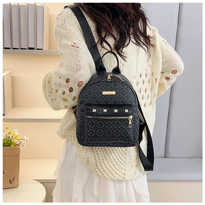 Détail du mini sac à dos noir avec rivets dorés et imprimé monogramme sur le dos du modèle