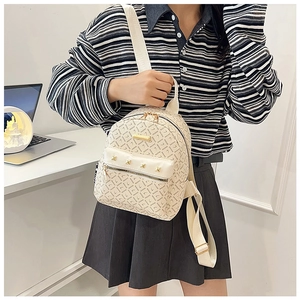 Détail du mini sac à dos crème avec imprimé logo et rivets dorés élégants
