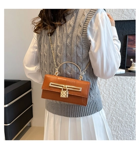 Detailsicht der orangefarbenen Kroko-Lederhandtasche mit Herzschloss und Metallgriff