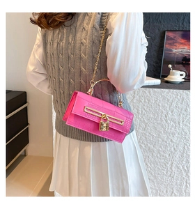 Detail of pink faux crocodile leather bag with gold chain strap and heart lock