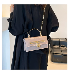 Detail der rosa Handtasche mit Krokodilprägung und goldenem Metallgriff am Modell