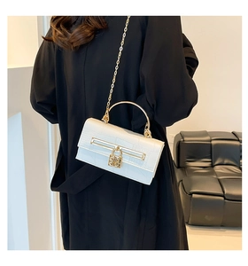 Detail der cremefarbenen Crossbody-Tasche mit Kroko-Prägung, Goldgriff und Kettenriemen