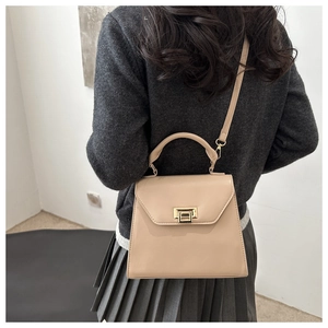 Vue latérale d'un sac beige avec fermoir doré porté à l'épaule par un mannequin